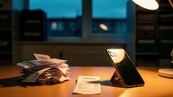 A small UK accountancy office at dusk, a desk with a stack of paper receipts and a smartphone photographing one, warm desk lamp light against a cool blue window reflection, shallow depth of field, no