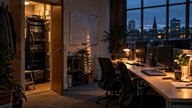 A small UK tech startup office at dusk, a single server rack visible through an open comms cupboard door beside a row of empty desks, laptops closed, one whiteboard with sketched boxes and arrows, war